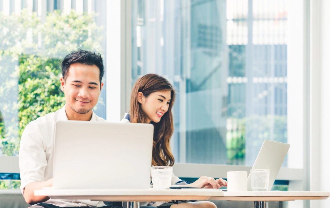 Smiling coworkers using laptops together